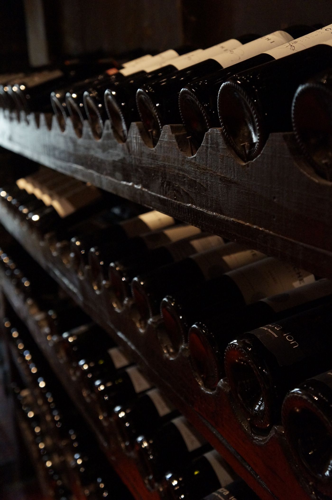 Cave à vin tamisée aux étagères de bois garnies de bouteilles